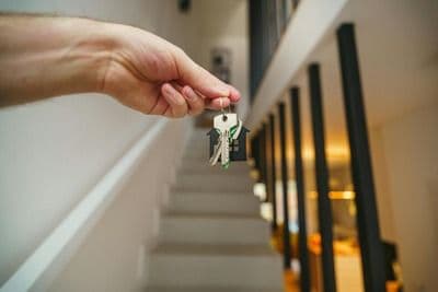 Someone holding house keys by stairs
