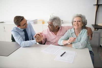 Three people sitting at a table signing up for life insurance