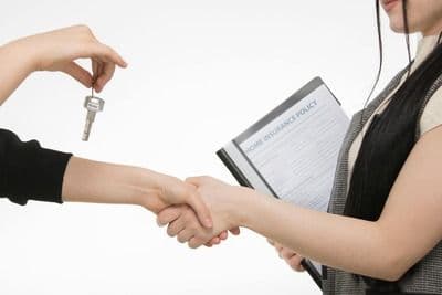 A Broker Handing the Key to Her Client after getting Home Insurance