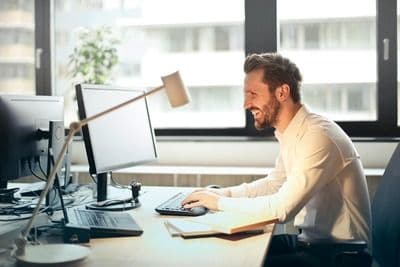 A man working from a desk with a smile